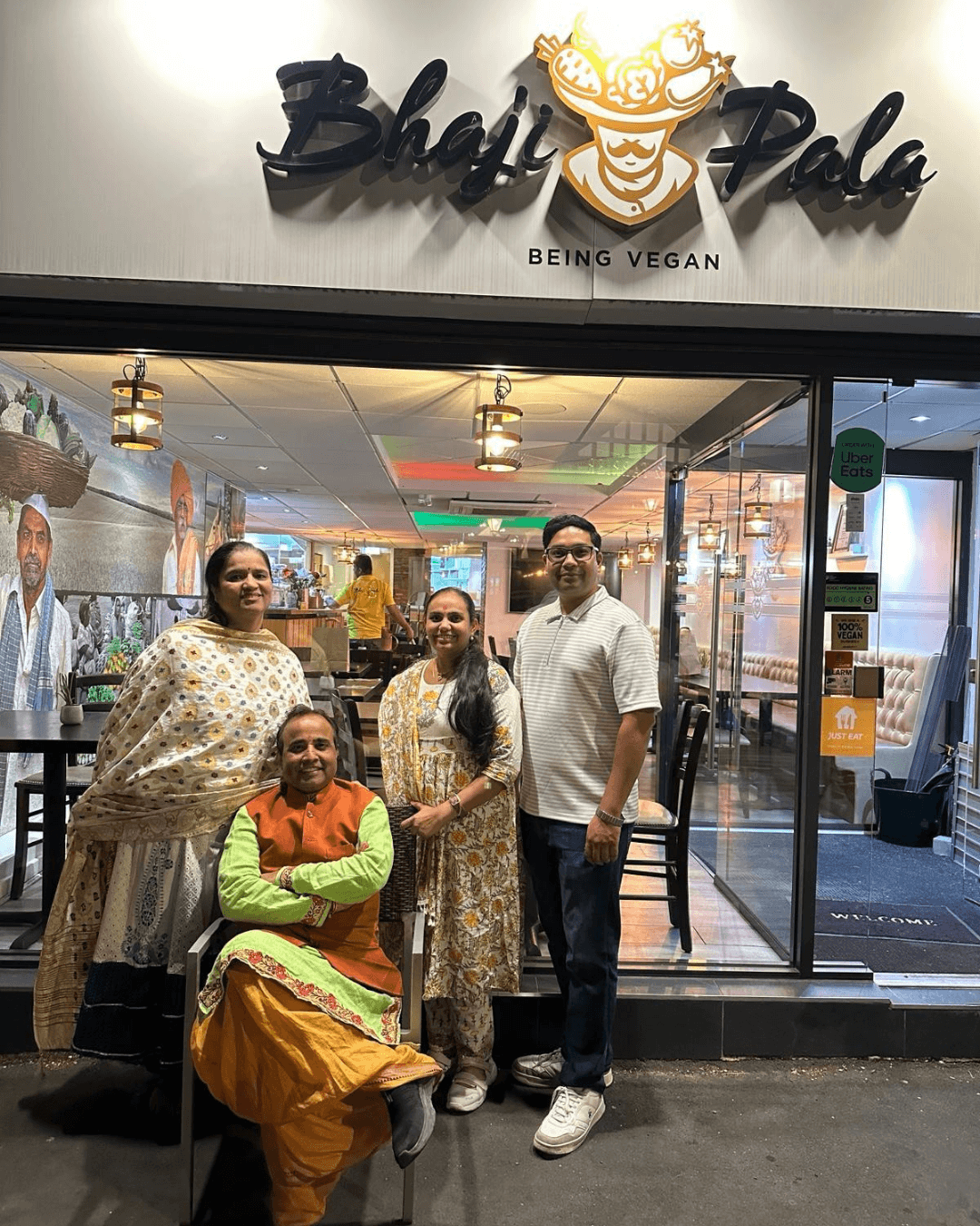 The Bhajipala founding family outside the restaurant, beneath the Bhaji Pala 'Being Vegan' sign